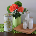 Vintage rusk container displayed with vintage milk bottles, green pitcher and orange roses. @FanningSparks