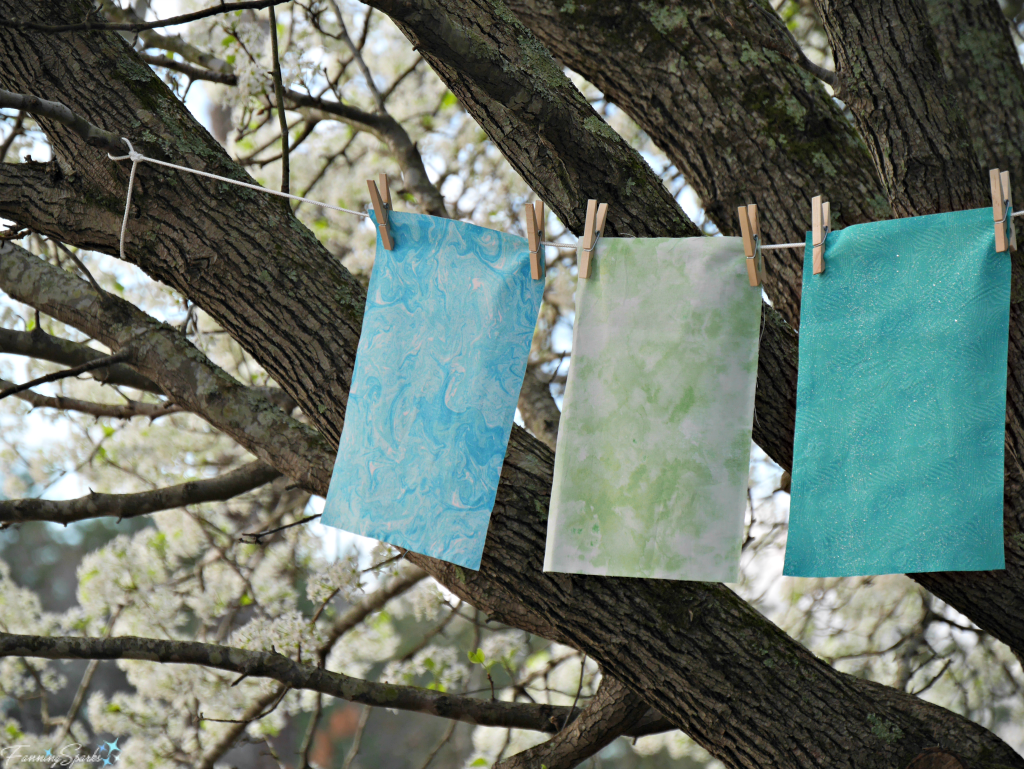 Blue, green and turquoise fabric on clothesline in blooming pear tree. @FanningSparks