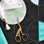 Sample of reverse applique in progress includes stork scissors, embroidery floss and fabrics. @FanningSparks