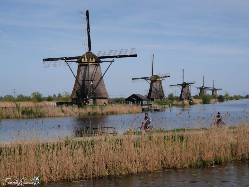 Cyclists in Front of Row of Kinderdijk Windmills   @FanningSparks